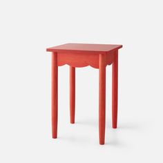 a small red table with an oval shaped top and two legs on the bottom, in front of a white background