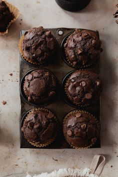 chocolate muffins sitting on top of a baking pan next to a cupcake tin