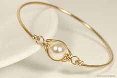 Gold Ivory Pearl Bracelet Handmade by Jessica Luu Jewelry ~ Sophisticated ~ Ladylike ~ Romantic ~ Perfect for everyday wear, this bangle adds a touch of casual elegance to every occasion - available with matching earrings. FIT NOTE: This bangle slides over the hand and does not open, so please choose your hand size and not wrist size.  MATCHING ITEMS https://www.etsy.com/shop/JessicaLuuJewelry?search_query=cream BRACELET MATERIALS: ~ 10mm cream crystal nacre pearl ~ 14K gold filled wire EARRINGS DETAILS: ~ 8mm cream crystal nacre pearls ~ 14k gold filled wire ~ .9 inches long HOW IT'S MADE: A large pearl is wire wrapped in a herringbone style then attached to a bangle bracelet that has been formed by hand, hammered for strength, and tumbled to a high shine. Gold filled wire is a hollow tub Elegant Wire Wrapped Pearl Bracelet, Elegant White Wire Wrapped Pearl Bracelet, Elegant Adjustable Wire-wrapped Pearl Bracelet, Elegant Adjustable Wire Wrapped Pearl Bracelet, Elegant Adjustable Cream Jewelry, Elegant Wire Wrapped Pearl Bangle Bracelet, Elegant Wire Wrapped Wedding Bracelets, Elegant Wire Wrapped Bracelets As Gifts, Elegant Handmade Bracelets As Bridesmaid Gift