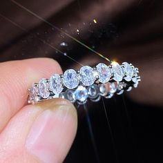 a close up of a person's hand holding a ring with diamonds on it