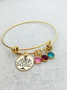 "This listing includes a gold plated stainless steel bangle bracelet. Bracelet includes a 5/8\" nu gold, brass disc hand stamped with tree and gold plated Swarovski birthstone crystal charms. PLEASE INCLUDE IN THE NOTE TO SELLER SECTION AT CHECKOUT THE BIRTHSTONES NEEDED IN THE ORDER YOU WOULD LIKE THEM ON THE BANGLE. Nu-gold is a copper alloy consisting of 85% copper and 15% zinc. It has a rich warm color and if highly polished resembles gold. This is also known as jewelers brass and will tarni Gold Bangle With Birthstone For Gift, Nickel-free Gold Bangle Charm Bracelet, Gold Bangle With Birthstone As Gift, Gold Nickel-free Bangle Charm Bracelet, Personalized Stackable Gold Jewelry, Gold Birthstone Bracelet For Mother's Day, Gold Nickel-free Bangle As Gift, Gold Bangle Bracelet With Birthstone, Gold Round Bracelet With Birthstone