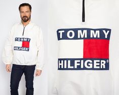 "Vintage 90s men's oversize pullover windbreaker jacket in white with the Tommy Hilfiger logo screen printed on the front and back. Measurements and Condition: Fits like: Labeled one size fits all (fits up to men's XL) Fabric: Nylon/poly Brand: None, made in USA - not official Tommy Hilfiger Condition: Very good, with light general wear. Length: 27.25\" Chest: 52\" Waist: 40\" to 48\" Shoulders (seam to seam): 20\" Sleeve: 25\" Shown on a 6' model, who usually wears shirt size medium and waist s Oversized White Windbreaker For Streetwear, White Oversized Sporty Windbreaker, Sporty White Oversized Windbreaker, White Graphic Print Windbreaker For Streetwear, 90s Style White Windbreaker For Spring, 90s Style White Windbreaker For Fall, White 90s Windbreaker For Fall, 90s Style White Windbreaker For Outdoor, White 90s Style Windbreaker For Outdoors