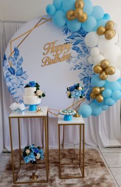 two tables topped with cakes and balloons in front of a happy birthday sign