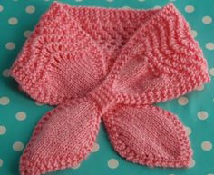 a pink knitted scarf laying on top of a polka dot table