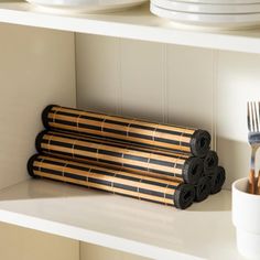 two bamboo utensils are sitting on the shelf next to plates and cups with forks in them