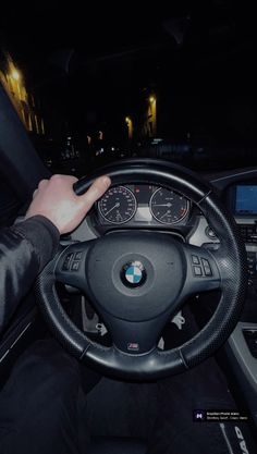 a person driving a car at night with their hand on the steering wheel and dashboard