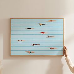 a person holding up a painting with swimmers on it