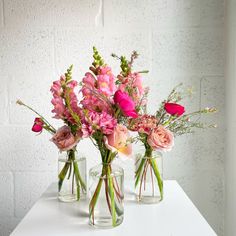 three glass vases with pink flowers in them