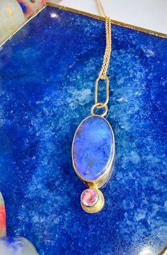 This stunning Lightning Ridge Black Opal is set in an 18k yellow gold bezel on a sterling silver backplate. The opal measures 22 mm by 12 mm. It is accented with a 4 mm Pink Tourmaline set in 18k yellow gold. Chain not included. Lightning Ridge Black Opal, Multicolor Jewelry, Handmade Silver Jewellery, 18k Gold Jewelry, Lightning Ridge, Crown Jewels, Yellow Gold Chain, Opal Ring, Black Opal