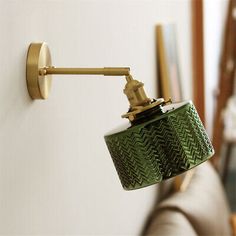 a green lamp is on the wall next to a couch