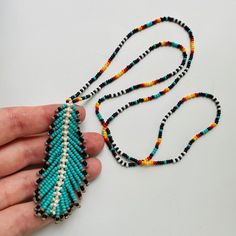 a hand holding a beaded necklace on a white surface