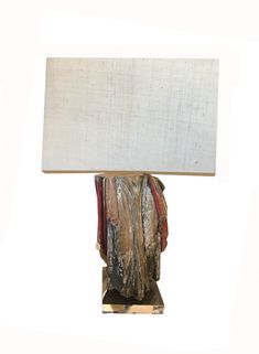 a lamp that is sitting on top of a wooden base with a white shade over it