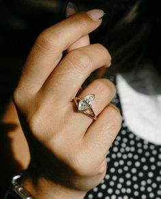 a woman's hand with a diamond ring on her left hand and a polka dot shirt on the right