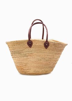 a straw bag with leather handles on the front and side, against a white background