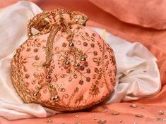 Peach Potli Bag with Pearl Handle Strap With its classy zari work and a pearl handle strap all in gold, this Peach Potli Bag is ideal for this wedding season. Fabric: Raw Silk Color: Peach Embroidery: Zari Work in Gold Size & Dimensions: Height - 8 inWidth - 7.5 inDepth - 1.5 in Strap: Pearl Handle Strap Closure: Tasseled Drawstring Compartments: Single compartment Care: Wipe with a soft, clean & dry cloth to remove dust When not in use, store it in a dust bag for longer product life Avo Hand Embroidered Bedspread, Peach Embroidery, Colorful Clutch, Embroidered Clutch Bag, Potli Bag, Raw Silk Fabric, Designer Clutch Bags, Embroidered Clutch, Potli Bags