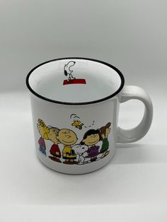 a white coffee cup with cartoon characters painted on the side and inside it's rim