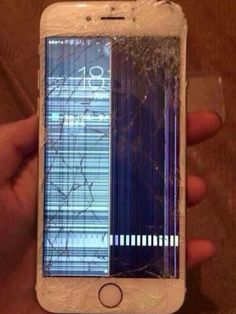 an iphone that has been cracked and is being held in someone's hand