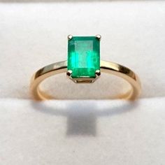 an emerald ring sitting on top of a white surface