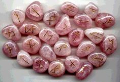 pink rocks with gold writing on them and zodiac signs in the middle one is surrounded by smaller stones