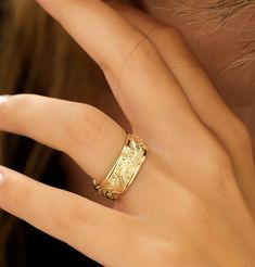 a woman's hand with a gold ring on top of her finger and an earring in the middle