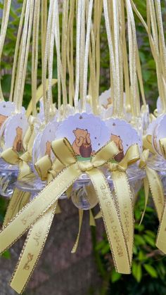 some wine glasses hanging from a tree with yellow ribbons and tags attached to the strings