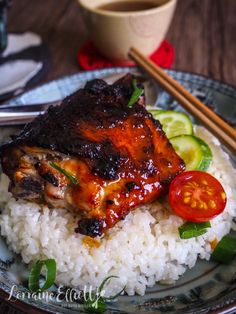 a plate topped with rice and meat next to chopsticks