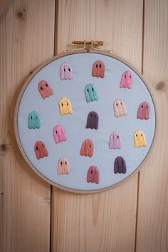 an embroidered wall hanging with elephants in pastel pink, yellow and green on it