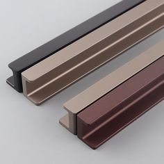 two different colored metal bars on a white surface with one black and one gold color