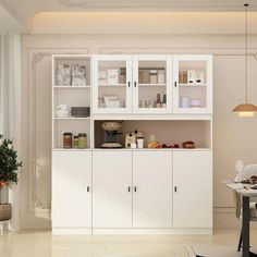 a white kitchen with lots of cupboards and shelves on the wall next to a potted plant