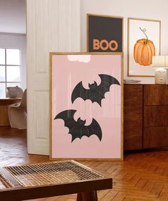 two bats are hanging on the wall next to a wooden table with a pumpkin in the background