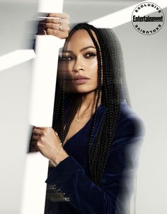 a woman with long braids leaning against a pole