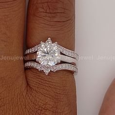 a woman's hand with a diamond ring on top of her finger and the other hand holding an engagement ring