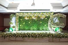 a stage set up with flowers and greenery