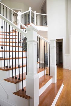 an open staircase with black railings and wood flooring in a large white home