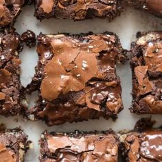 brownies with chocolate frosting and sprinkles are arranged on a white surface