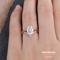 a woman's hand with a diamond ring on top of her finger and an engagement band