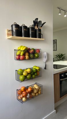 two metal baskets filled with fruit on top of a wall