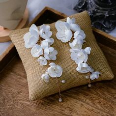 two white flowers are sitting on top of a pillow in front of some other items