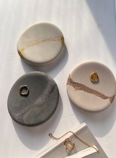 three different types of jewelry sitting on top of a white table next to a book