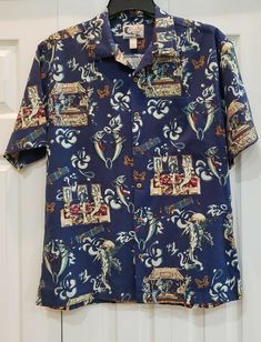 BLUEWATER WEAR MEN'S CAMP SHIRT WITH GREAT GRAPHICS! Men's Size Large BLUEWATER WEAR Tropical Camp Shirt with Wood Buttons and Pocket on Left Chest. Shirt has Allover 1950s Style Print Featuring Fish as "Rat Pack" Smoking Cigars & Drinking Cocktails, Tiki Piano Bar, Musicians, and Dancing. Pre-owned Condition. MEASUREMENTS Pit to Pit:  23" Shoulder to Hemline: 30" Blue Casual Shirt With Vintage Print, Casual Blue Shirt With Vintage Print, Vintage Blue Beach Shirt, Blue Vintage Beach Shirt, Blue Short Sleeve Shirt With Vintage Print, Blue Vintage Print Short Sleeve Shirt, Blue Short Sleeve Hawaiian Shirt With Vintage Print, Blue Hawaiian Shirt With Vintage Print, Vintage Blue Camp Shirt For Vacation