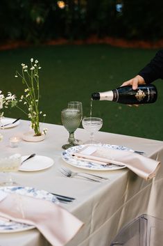 a person pouring wine at a table with plates and silverware