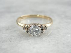 an engagement ring with three stones on the front and side, set in yellow gold