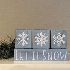 three snowflakes are painted on wood blocks with the words let it snow written in white