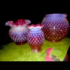 three glass vases sitting on top of a green table covered in pink and purple dots