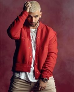 a man in a red cardigan and khaki pants poses for a photo