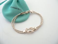 Do you know which items made Tiffany a world renowned company? You just stumbled upon one of them! Offered for sale is a wonderful vintage Tiffany and Co. Sterling Silver Double Rope Love Knot bracelet - in a rare longer length - 7.75 inches. The piece is made from solid and substantial Tiffany silver, yet has a very delicate and feminine feel to it. The bracelet is very unique - hard to find and come by, so grab it while you have the chance! It is very pretty worn on its own, but would also wor White Gold Jewelry With Clasp For Gift, Elegant Sterling Silver Bracelet With Clasp For Gift, Elegant Sterling Silver Bracelet With Box Clasp As Gift, Luxury Bracelets With Sterling Silver Clasp For Anniversary, White Gold Bracelets With Clasp, Love Knot Bracelet, Vintage Tiffany, Knot Bracelet, Tiffany And Co