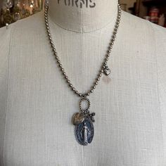 Necklace composed of vintage ball chain, small hook and eye set and three petite pendants, a heart, cross, and a small vintage heart locket inscribed with a cross. Necklace measures 18 inches in length, plus 1.25 inch vintage immaculate medal. Sold by the piece, limited to stock on hand. Silver Spiritual Necklace With Vintage Charm, Spiritual Silver Necklace With Vintage Charm, Vintage Sterling Silver Heart Charm Necklace, Vintage Cross Charms Jewelry, Spiritual Heart Necklace With Vintage Charm, Spiritual Heart-shaped Necklace With Vintage Charm, Spiritual Heart-shaped Vintage Charm Necklace, Vintage Silver Charm Necklace With Heart Pendant, Vintage Silver Heart Pendant Charm Necklaces