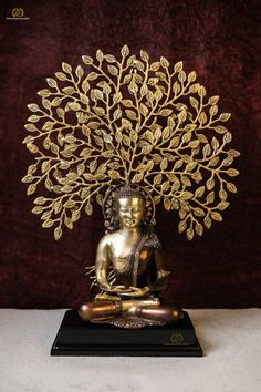 a golden buddha statue sitting under a tree