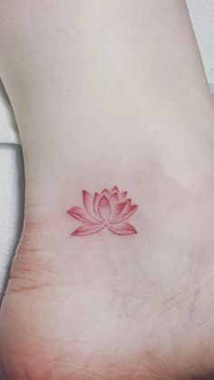 a small pink lotus flower on the side of a woman's foot with red ink