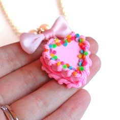 "This adorable miniature birthday cake necklace is a special way to celebrate your birthday or make everyday your birthday! It was inspired by all those fabulous kitschy and girly pink birthday cakes we had growing up. This cake is adorned with classic birthday cake details like pink piped frosting, frilly bright pink icing along the middle, and topped with bright rainbow confetti sprinkles. The cake hangs below a lovely pink bow from a high quality glass pearl beaded chain and silver plated cha Pink Heart Birthday Cake, Rainbow Sprinkles Cake, Classic Birthday Cake, Cake Necklace, Rainbow Sprinkle Cakes, Pinup Jewelry, Heart Birthday Cake, Sprinkles Cake, Circus Animal Cookie